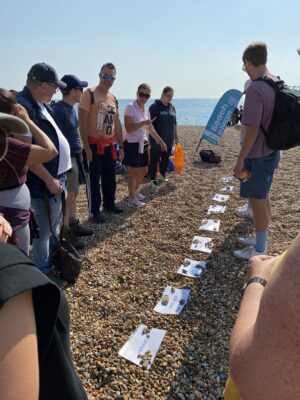 group of people on beach looking at timeline laid on pebbles