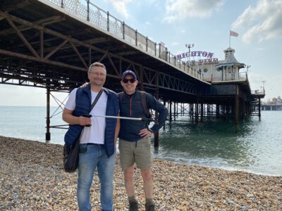 two people holding litter pickers on brighton beach in front of pier