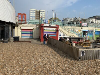 one person litter picking on brighton beach in front of shops